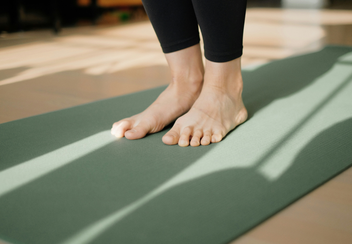 Pieds d'une femme debout sur un tapi de yoga 