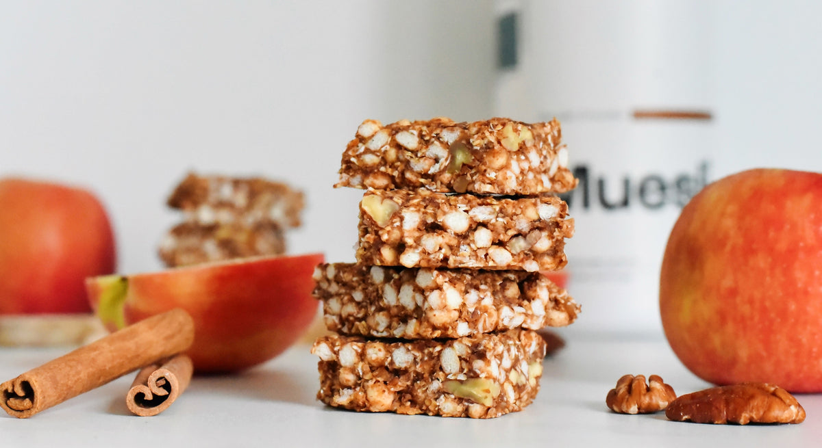 Morceaux de barre au muesli posés sur une table avec des pommes et bâtons de cannelle 